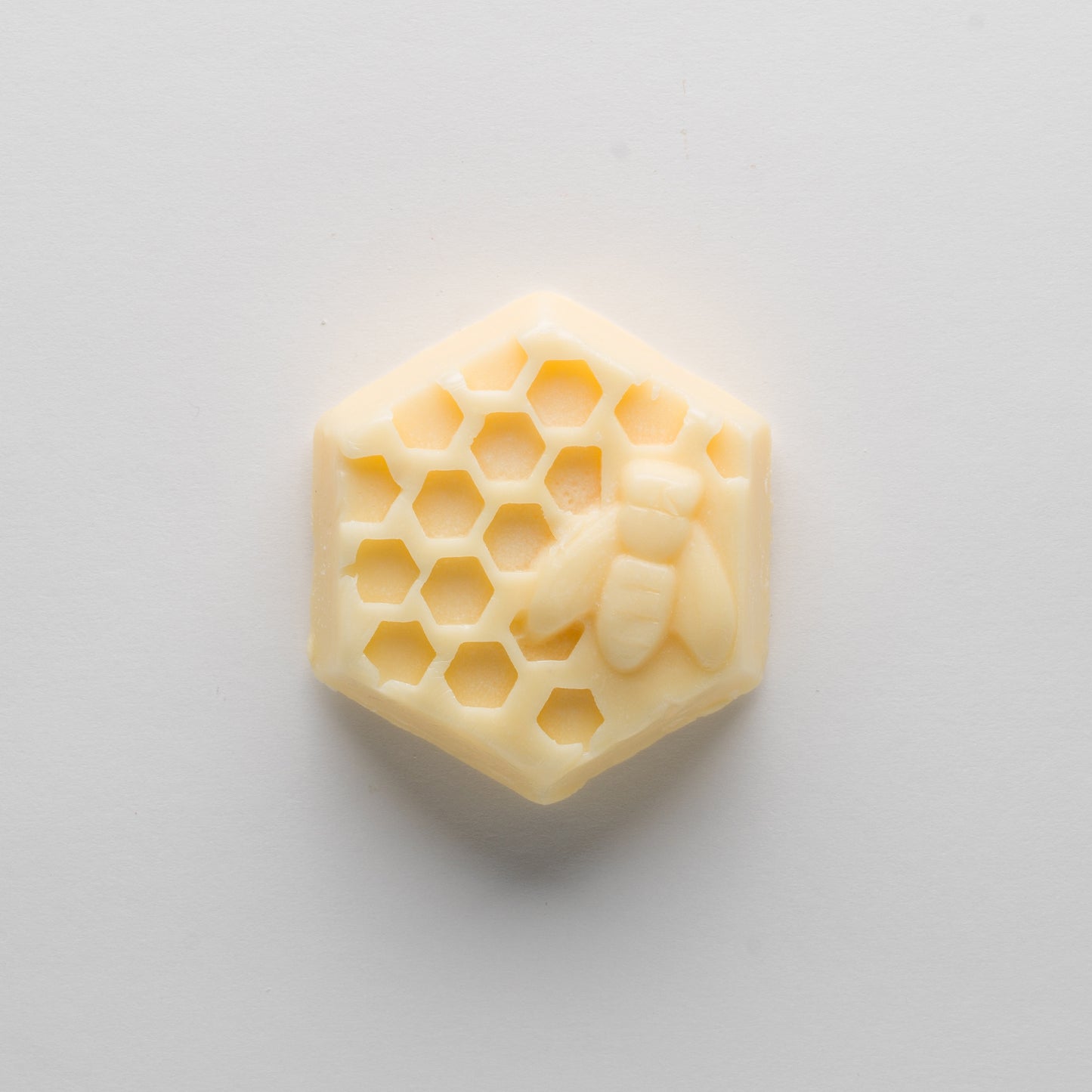 A cream-color hexagonal bar with a honey bee and honey comb  on a white background
