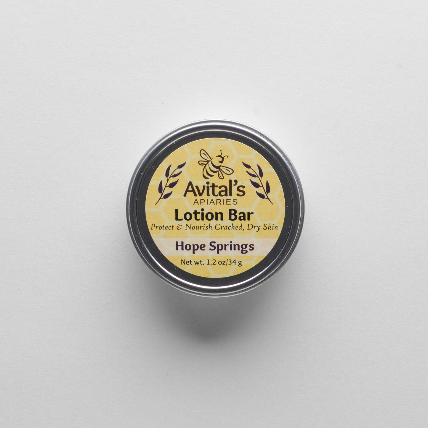 Overhead shot of a tin containing a Hope Springs Lotion bar. The label is a cheerful yellow  with a hexagon pattern and says "Lotion Bar. Proptect & Nourish Cracked, Dry Skin. Hope Springs. 1.2 oz