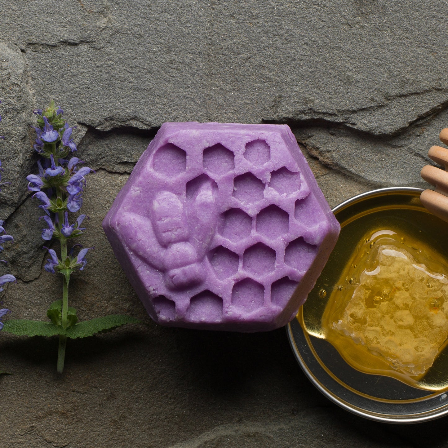 A purple hexagonal bar with a bee and hexagons depicted on it. To the left are springs of lavender and to the right a square of honey comb.