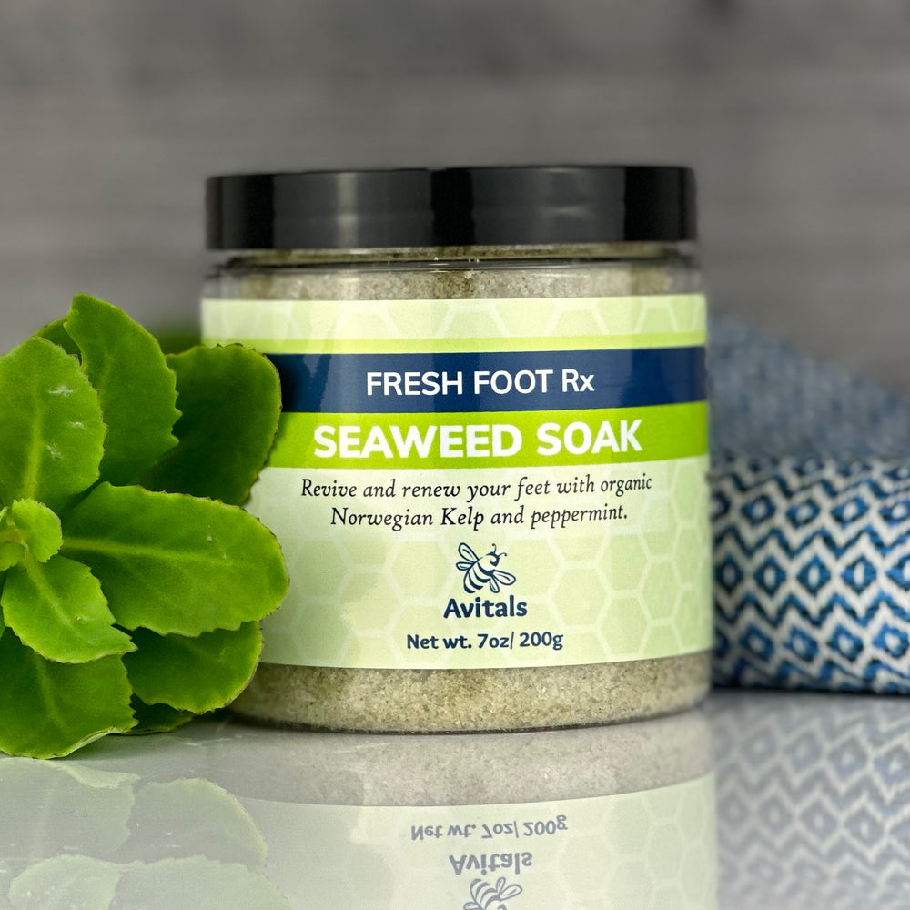 A jar of our Fresh Foot Rx Seaweed Soak with greenery and a towel