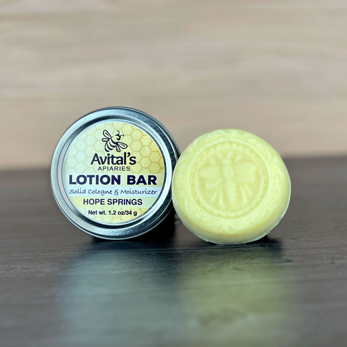 Lotion bar and container with 'Avital's Apiaries' branding on a wooden surface