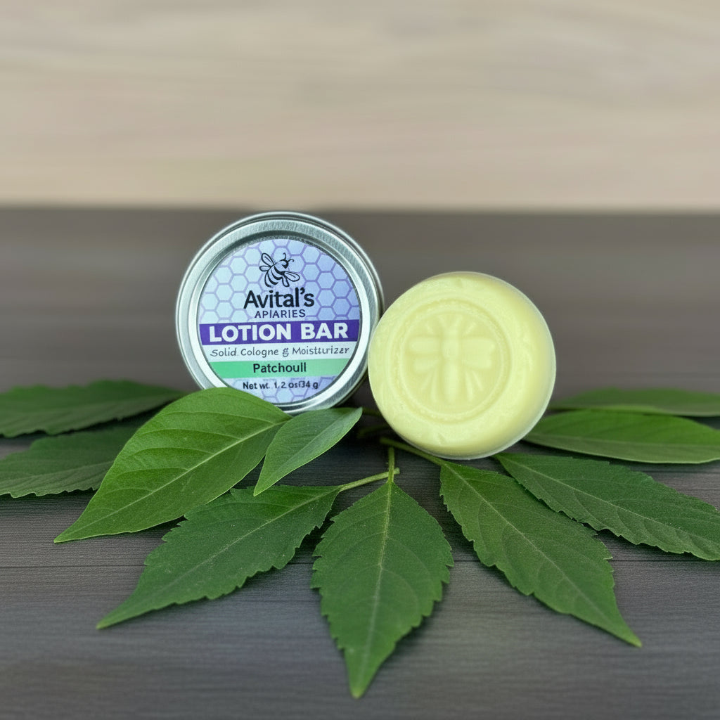 Avital's Apiaries lotion bar and container on a wooden surface with scattered patchouli leaves