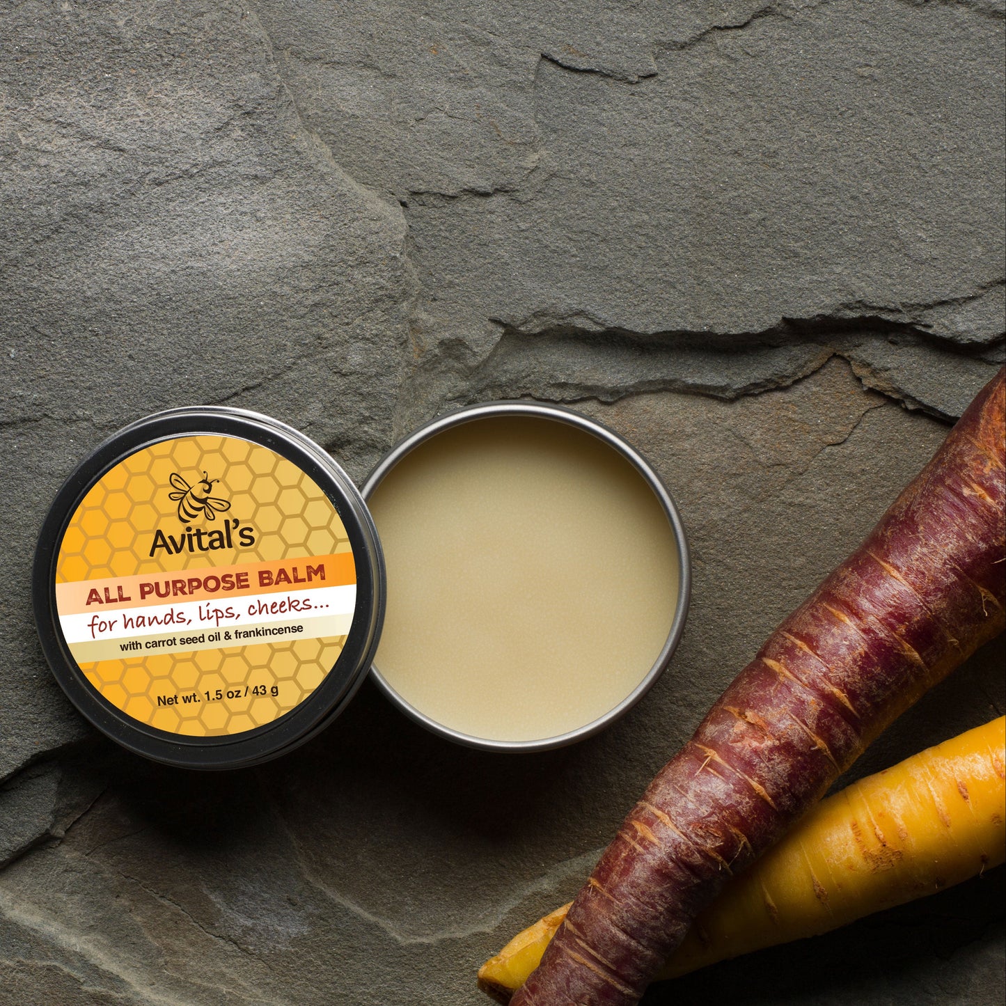 Avital's All Purpose Balm with a carrot on a stone surface