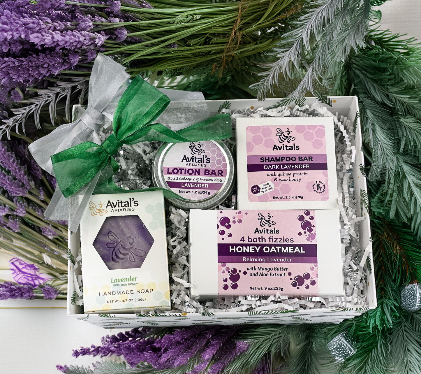 Lavender Lovers gift basket, including Honey Oatmeal bath fizzies, Shampoo bar, Lotion Bar, and soap. A green ribbon dresses up the market basket it isand surrounded by festive boughs.