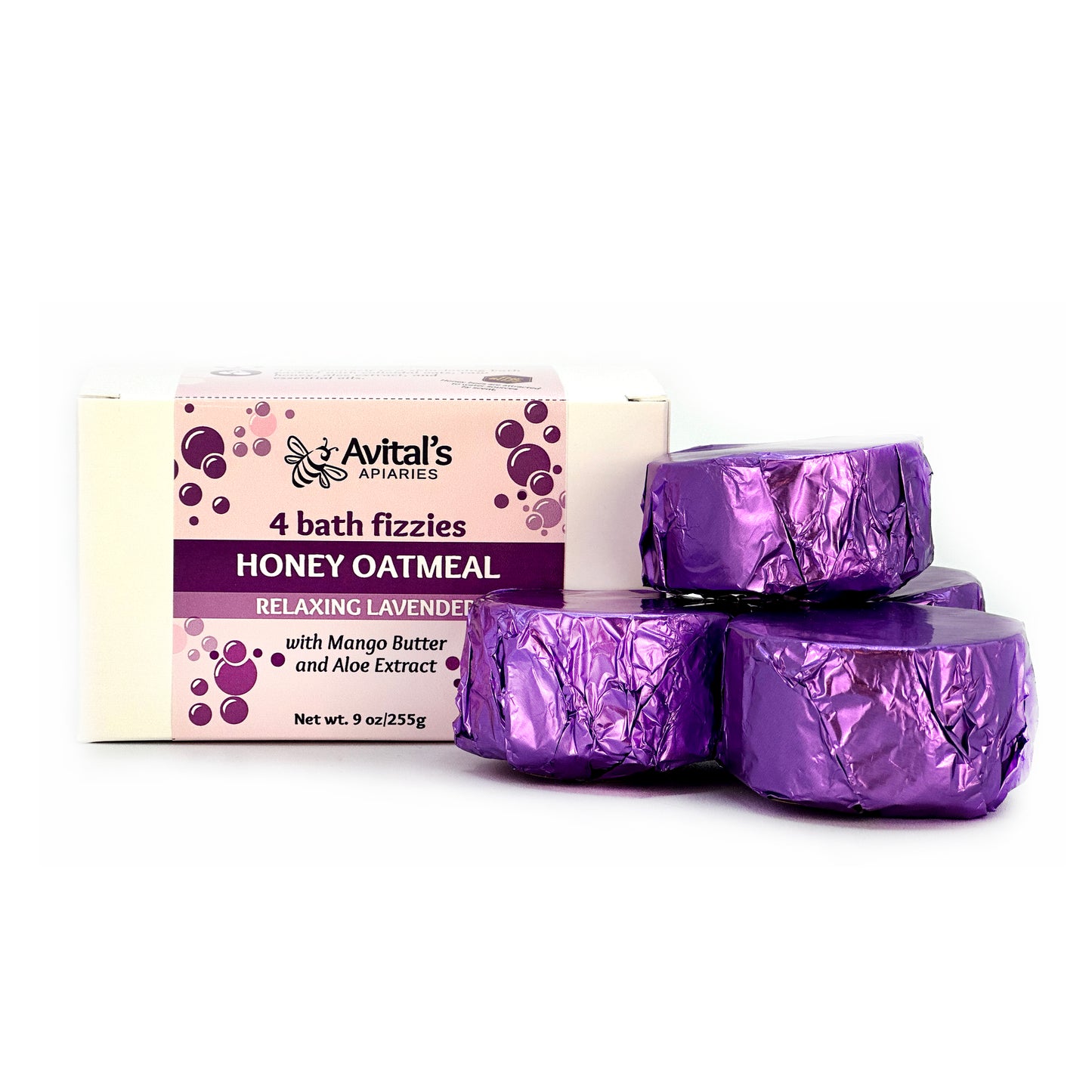 A white box with a purple label reading RElaxing Lavender Honey Oatmeal 4 bath fizzies. Four purple-foil wrapped fizzies are piled next to it.