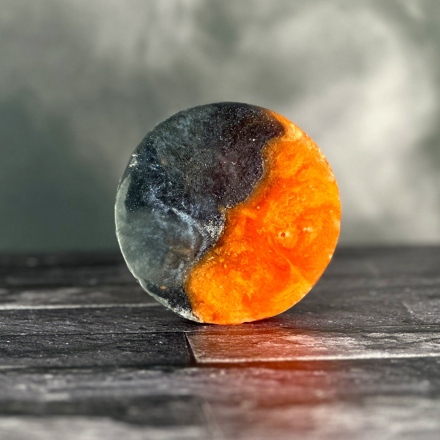 A black and orange bar on a black surface with swirls of smoke in the background.