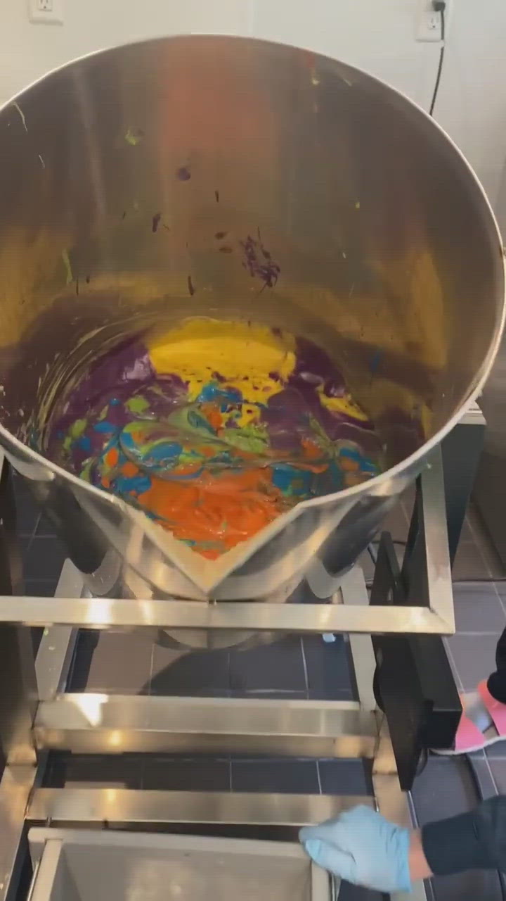 A video showing a multi-colored vat of soap being poured into a large mold.