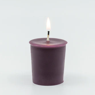 A lit, deep purple votive candle with a center wick.