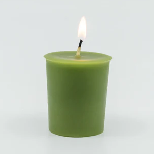 A lit green votive candle with a center wick.