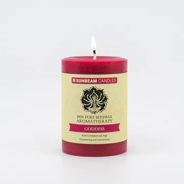 
                  
                    A reddish-pink lit pillar candle with a paper label.
                  
                
