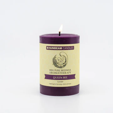 A deep purple lit pillar candle with a paper label.