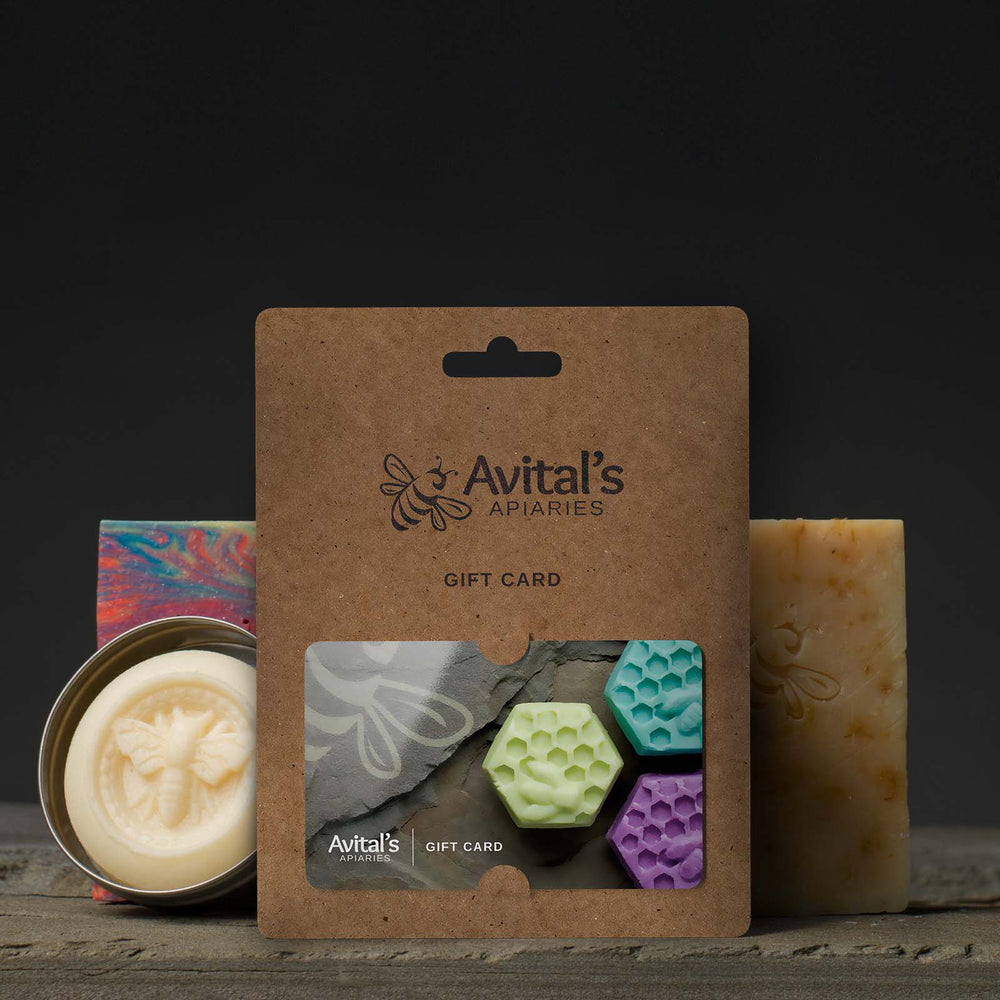 A kraft backing with a colorful Avital's Gift Card in the foreground. Behind it are soaps and a lotion bar.