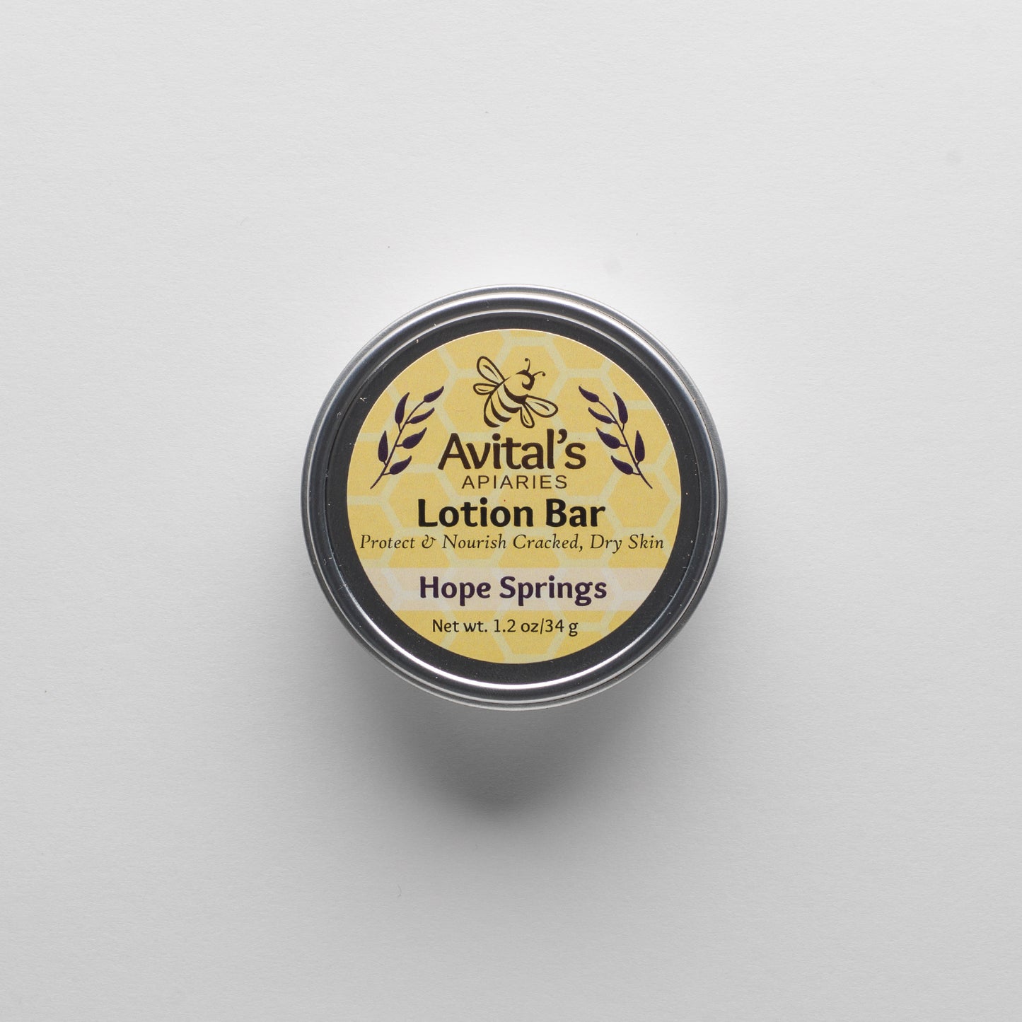 
                  
                    Overhead shot of a tin containing a Hope Springs Lotion bar. The label is a cheerful yellow  with a hexagon pattern and says "Lotion Bar. Proptect & Nourish Cracked, Dry Skin. Hope Springs. 1.2 oz
                  
                