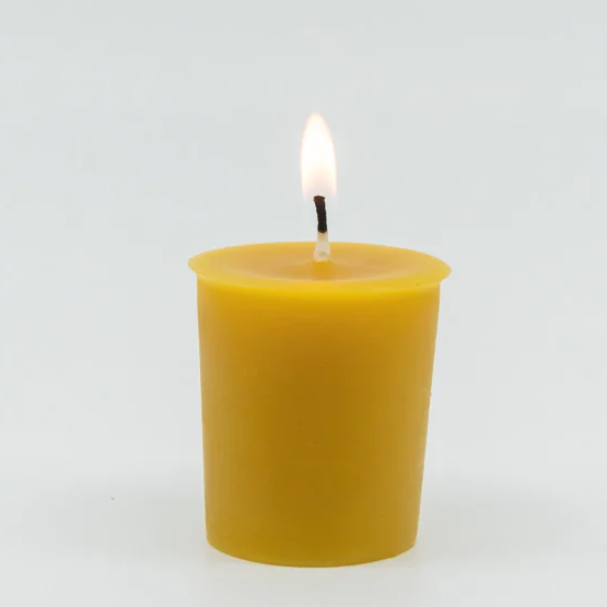  A yellow beeswax votive candle, lit.